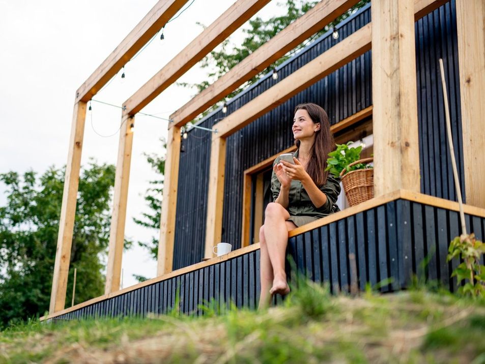 mujer sentada con el movil en el porche de una casa contenedor